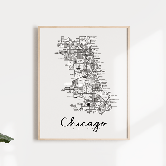Black and white map print of Chicago, Illinois, framed and displayed on a wall with leaves around it.