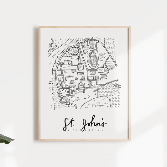 Black and white print of a hand-illustrated map of Saint John's University, titled 'St. John's', presented in a wooden frame with a white mat, displayed against a neutral background.