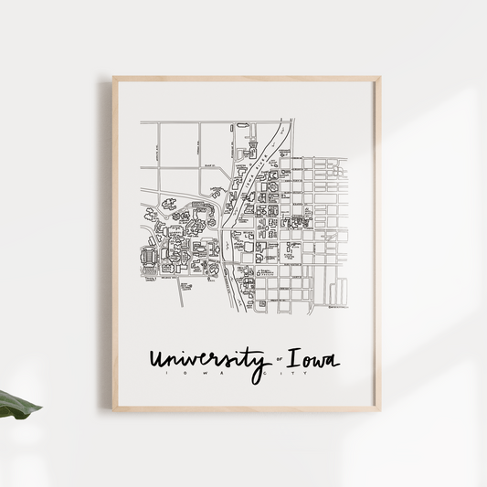 Black and white print of a hand-illustrated map design of the University of Iowa, framed and mounted on a wall with the text 'University, Iowa' at the bottom.