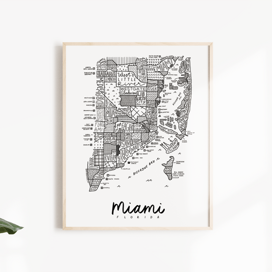 Framed map of Miami on a white wall with green leaves.